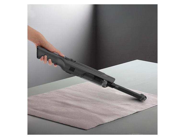 Handstofzuiger reinigt een placemat op tafel.