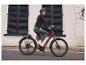Vrouw op een rode elektrische fiets, fietshelm.