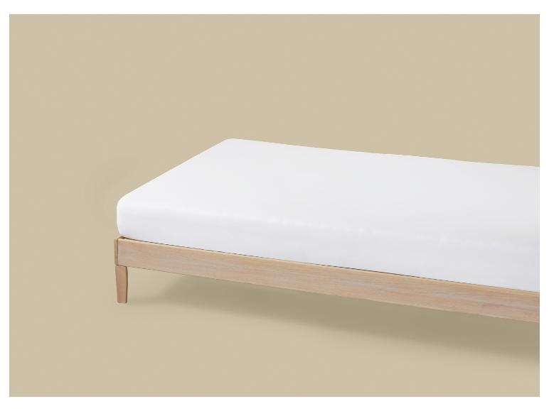 Een wit matras op een houten bedframe tegen een beige achtergrond.