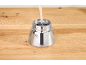 Water wordt in de zilveren basis van een koffiezetapparaat op een houten tafel gegoten.