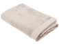 Opgevouwen beige badhanddoek met een wit etiket.