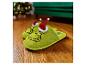 Groene Grinch-pantoffels met kerstmutsen op een houten vloer