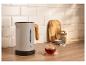 Moderne waterkoker met houten handvat, een kopje thee en theeaccessoires op een houten aanrecht.