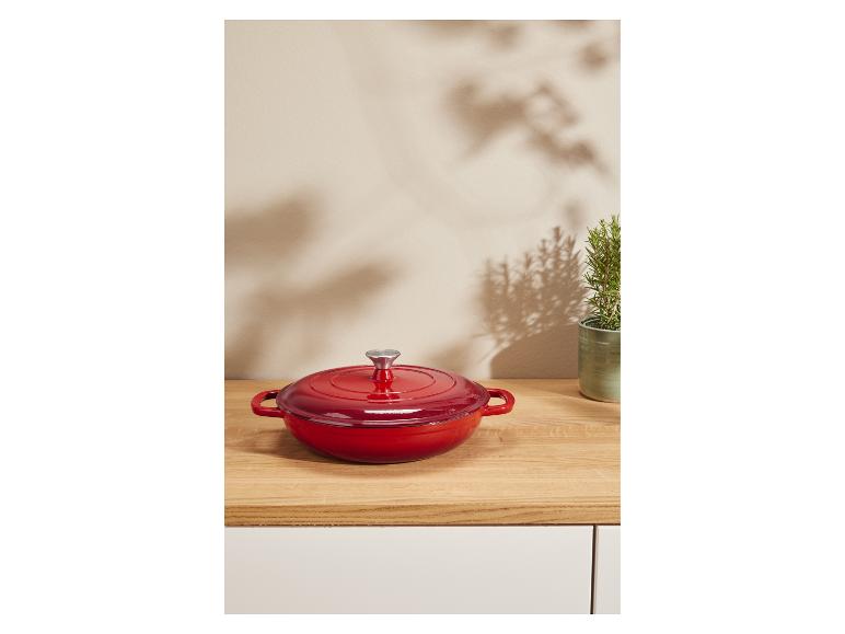 Rode gietijzeren pan op een houten aanrecht.