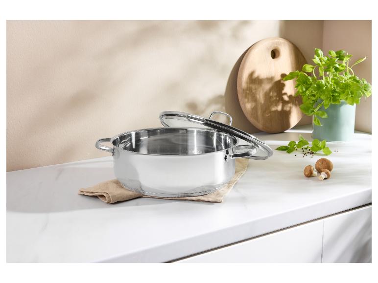 Roestvrijstalen pan met deksel op aanrecht met kruiden en champignons.