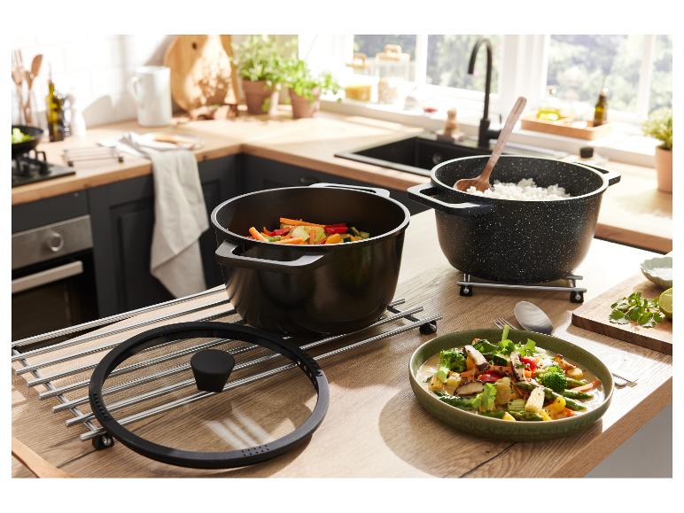 Twee zwarte pannen met eten op een houten tafel in de keuken.