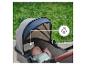 Baby slaapt in een kinderwagen met ademende kap, buiten in een park.