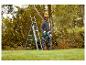 Man met veiligheidshelm en kettingzaag, naast een ladder, snoeit bomen.