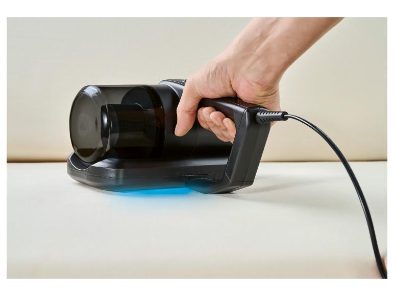 Handstofzuiger met blauw licht op een lichte ondergrond, vastgehouden door een hand.