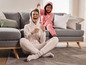 Twee vrouwen in pyjama's lachen en spelen op de bank.