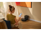 Vrouw gebruikt smartphone om robotstofzuiger te bedienen in lichte kamer.
