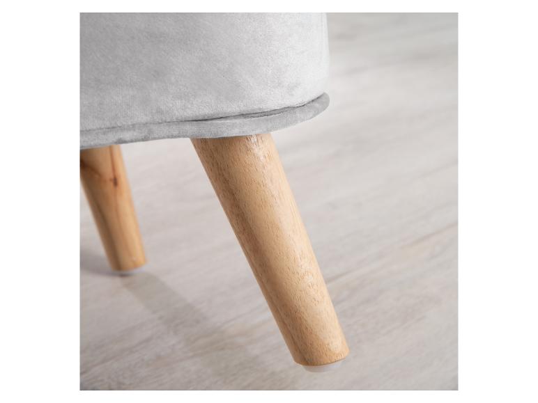 Grijze fluwelen kruk met houten poten op een lichte houten vloer