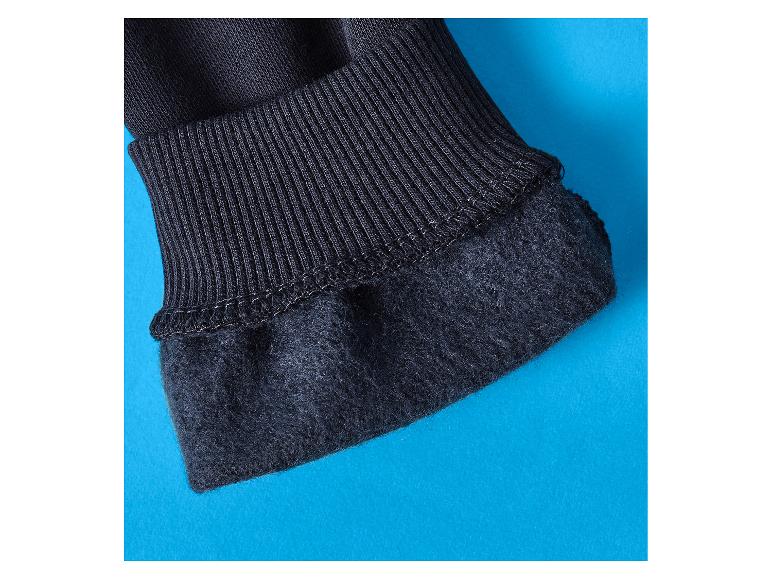 Close-up van een zwarte geribbelde manchet en gevoerde stof op een blauwe achtergrond.