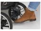 Voet in bruine laars en jeans, drukkend op de rem van een kinderwagen.