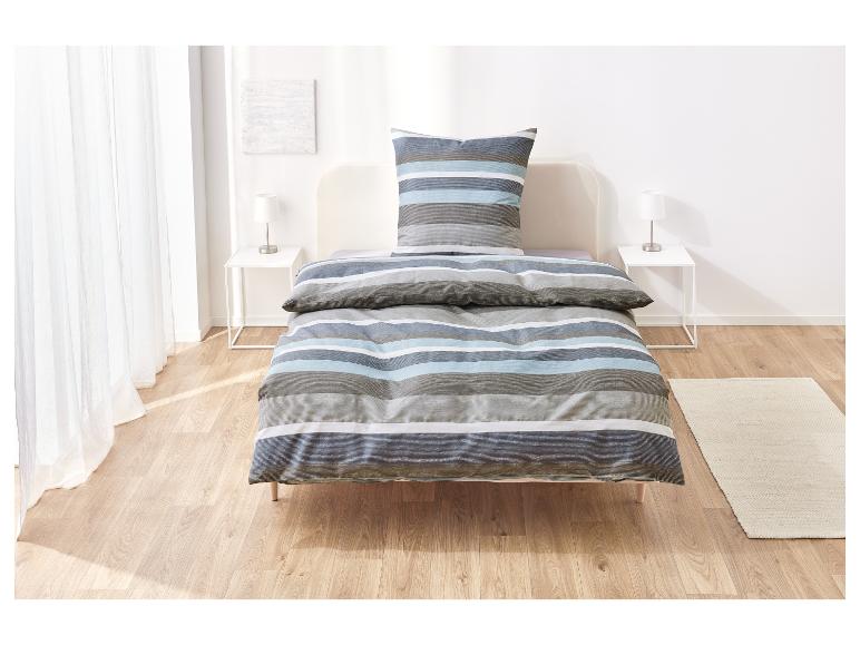 Gestreept beddengoed op een bed in een lichte slaapkamer.