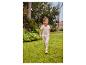 Lachend meisje in beige T-shirt en legging met hartjes, rennend op gras.