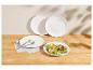 Witte borden met verse salade en bestek op een houten tafel.