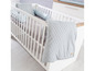 Babybed met wit houten frame, grijs dekbed en kussen.