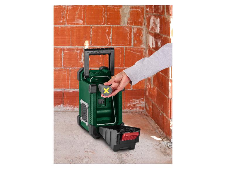 Persoon plaatst gele batterij in groene bouwradio.