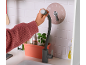 Kinderhand die de flexibele kraan van een houten speelgoedkeuken vasthoudt.