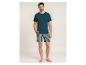 Man in donkerblauw T-shirt en gestreepte korte broek.