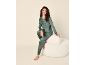 Vrouw in groene fluwelen pyjama zittend op een witte poef