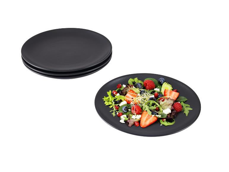 Zwarte borden met een bessensalade, feta en kiemen.