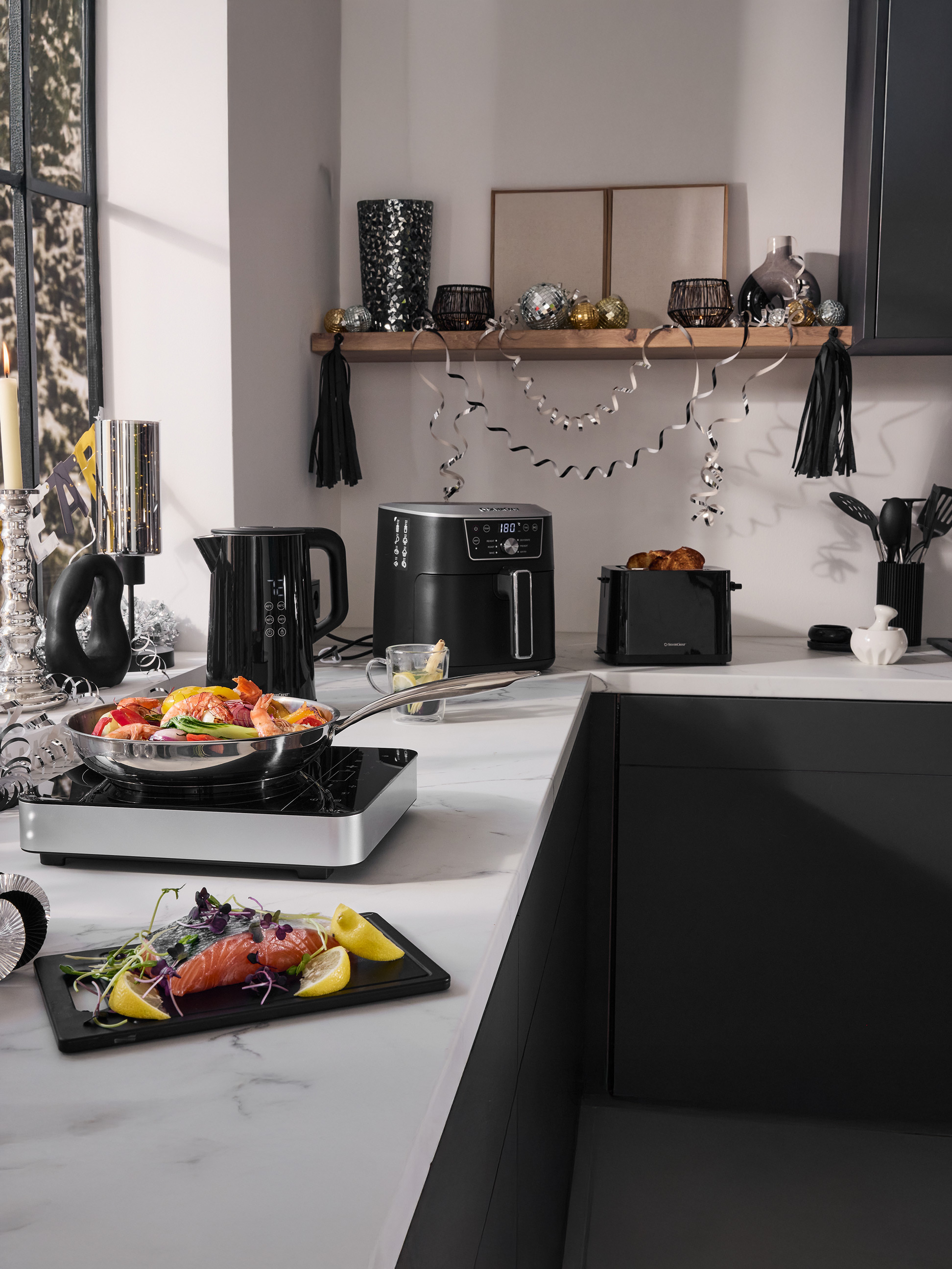 Keukenblad met SilverCrest airfryer, waterkoker, broodrooster en kookgerei, feestelijk versierd.