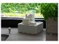 Witte drielaagse binnenfontein met stromend water, naast een basilicumplant.