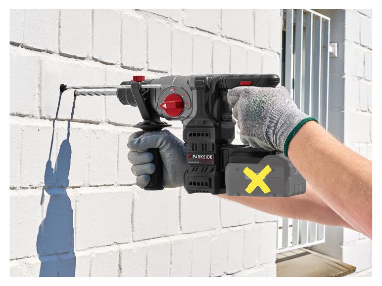 Man boort in een witte bakstenen muur met een draadloze boorhamer