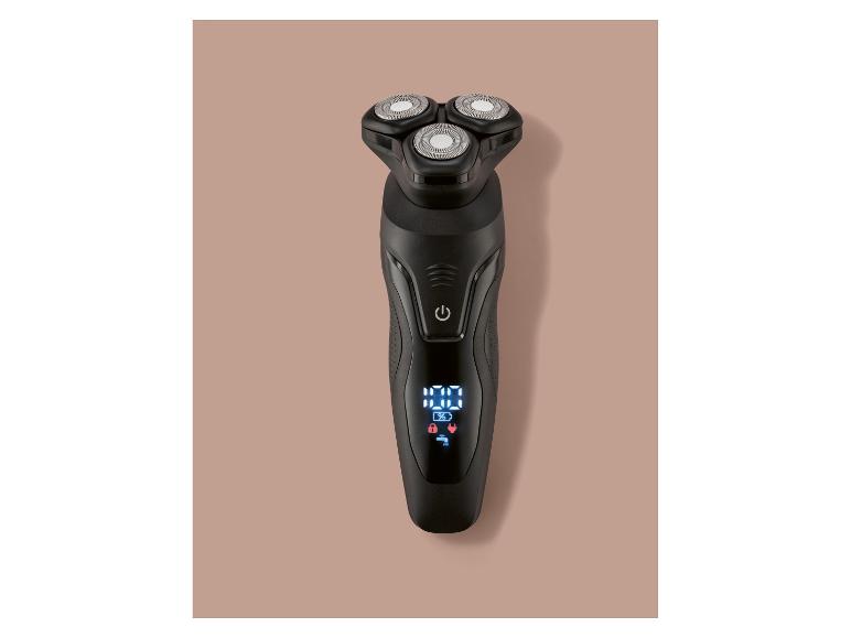Zwart roterend elektrisch scheerapparaat met digitaal display op een lichtbruine achtergrond.