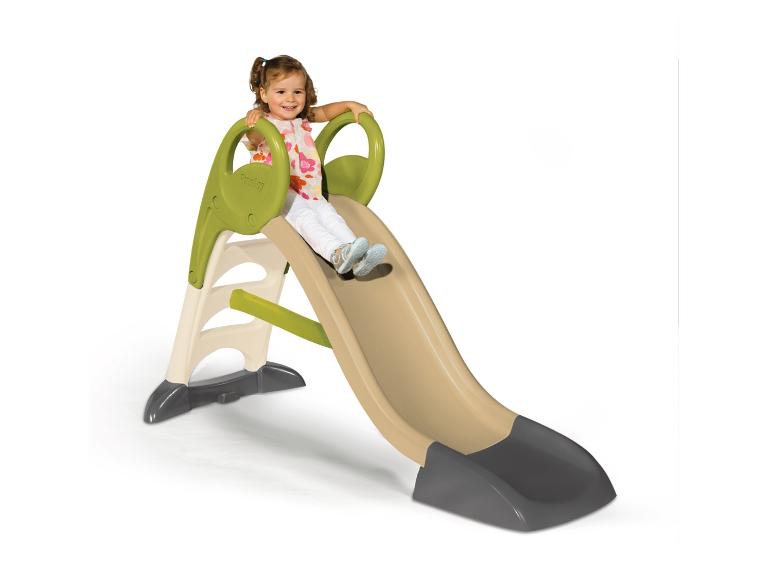 Lachend meisje glijdt van een beige en groene glijbaan.