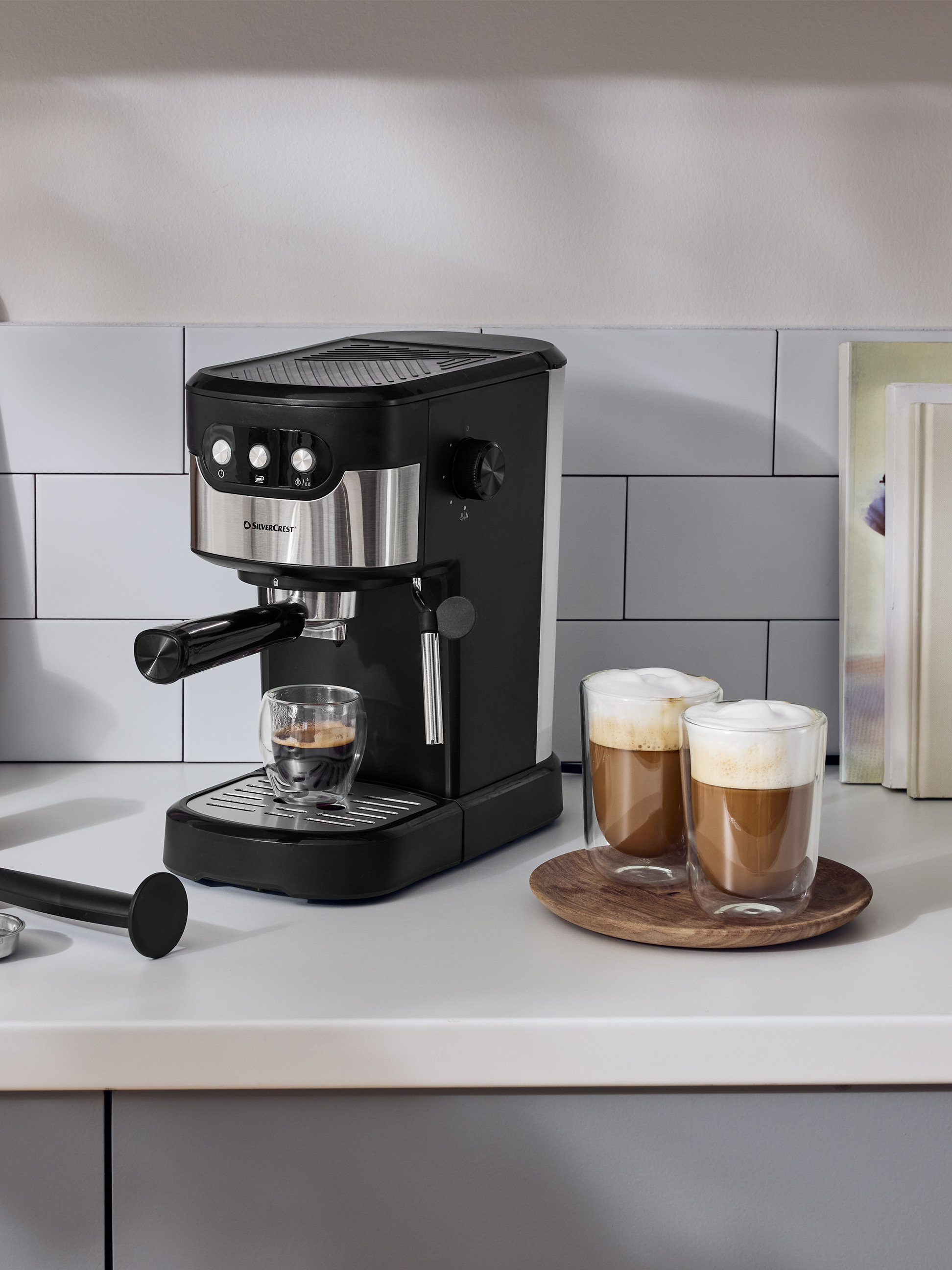 Zwart espressomachine op wit aanrecht met twee kopjes koffie.