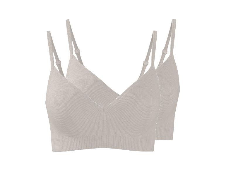 Twee lichtbeige geribbelde bralettes met verstelbare bandjes.