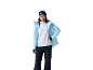 Vrouw in lichtblauwe ski-jas, witte fleece, donkerblauwe skibroek, grijze muts en skibril.