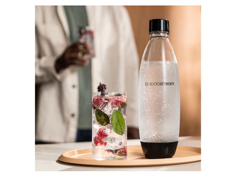 Een SodaStream-fles en een glas bruisend drankje met bessen en munt.