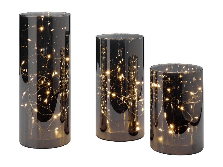 Drie cilindrische glazen lantaarns met warme sprookjeslichtjes erin, variërend in hoogte.