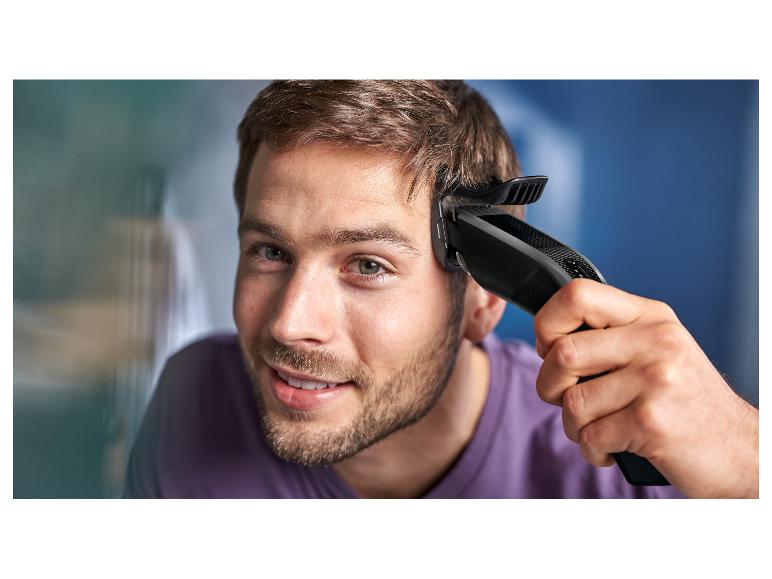 Jonge man gebruikt een elektrische tondeuse om zijn haar te knippen.