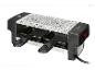 Een kleine raclette grill met een granieten kookoppervlak en twee zwarte pannetjes.