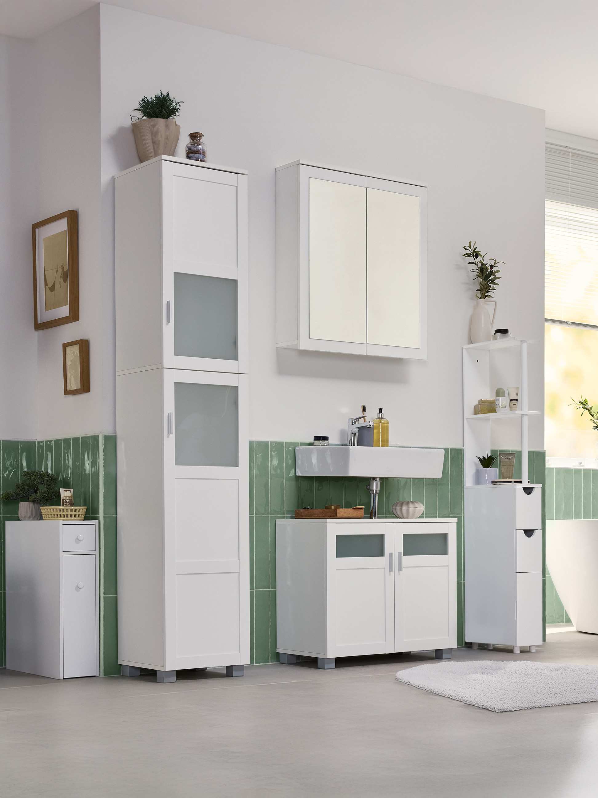 Badkamer met witte kasten, een wastafel en groene wandtegels.