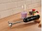 Zwarte staafmixer met bessensmoothie en fruit op een houten aanrecht.