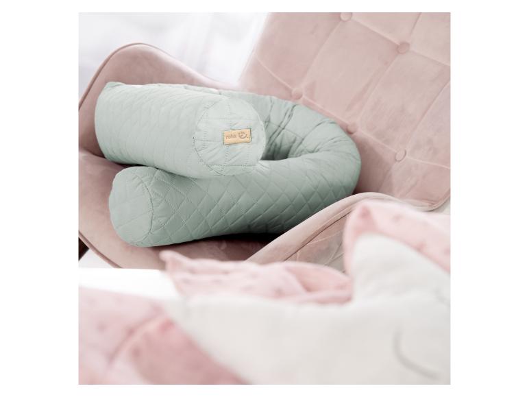 Mintgroen roba voedingskussen in een roze fauteuil.