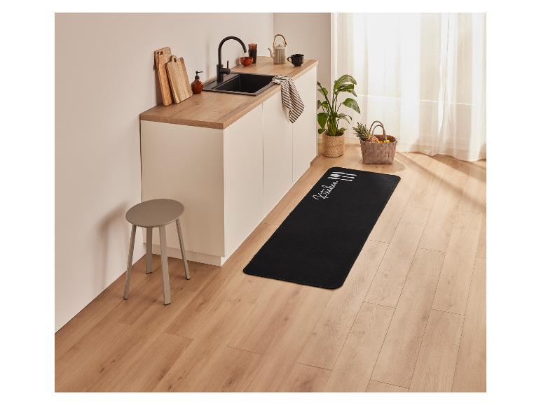 Een zwart keukenkleed met witte ontwerpen op een houten vloer.