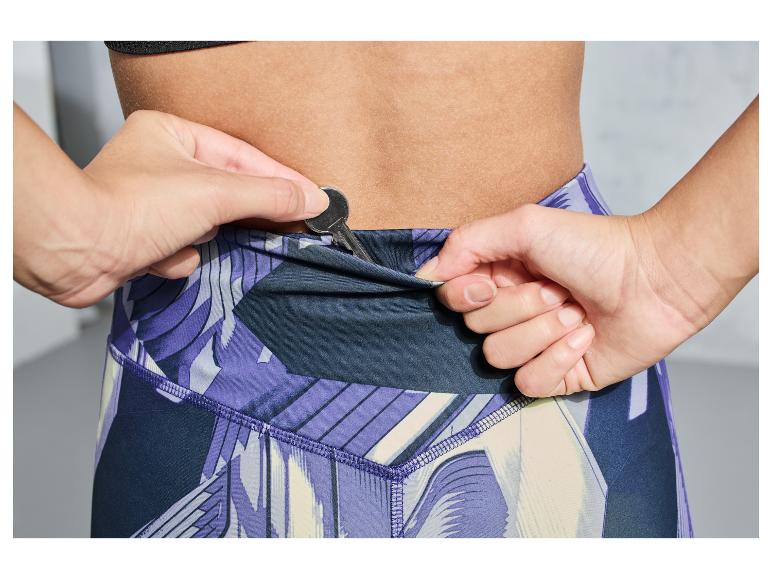 Een vrouw die een sleutel in de zak van haar sportbroek stopt.