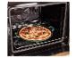 Vers bereide pizza in een groene bakvorm, geplaatst op een rooster in een open oven.