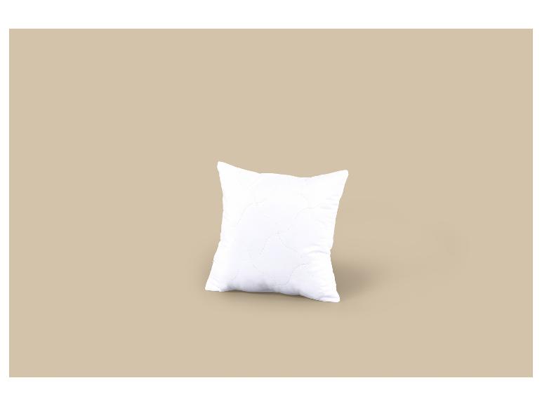 Wit kussen met golvend stikselpatroon op een beige achtergrond.
