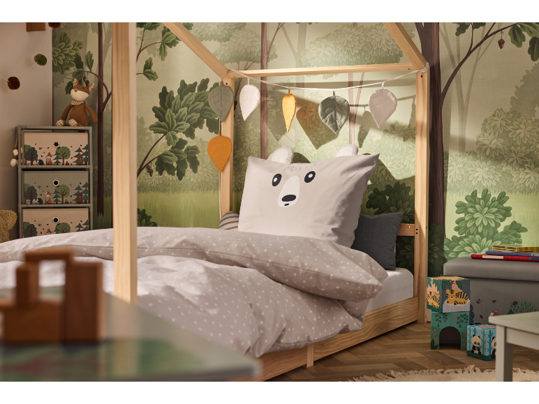 Kinderbed met bosbehang en beddengoed met dierenthema.