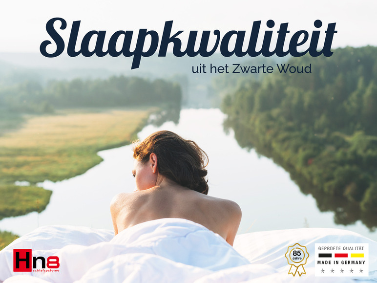 Een vrouw ligt op een wit laken van Hns8 met uitzicht op een rivier.