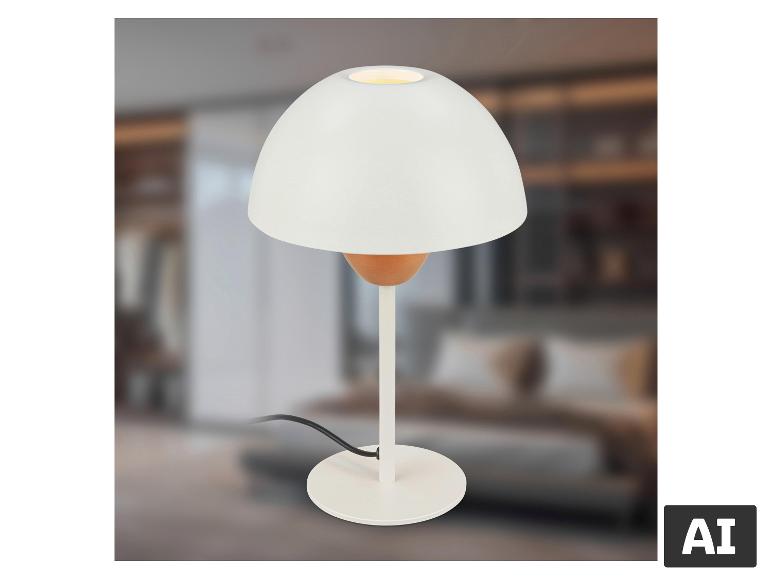 Witte tafellamp met ronde voet en koepelvormige kap, in een wazige slaapkamer.