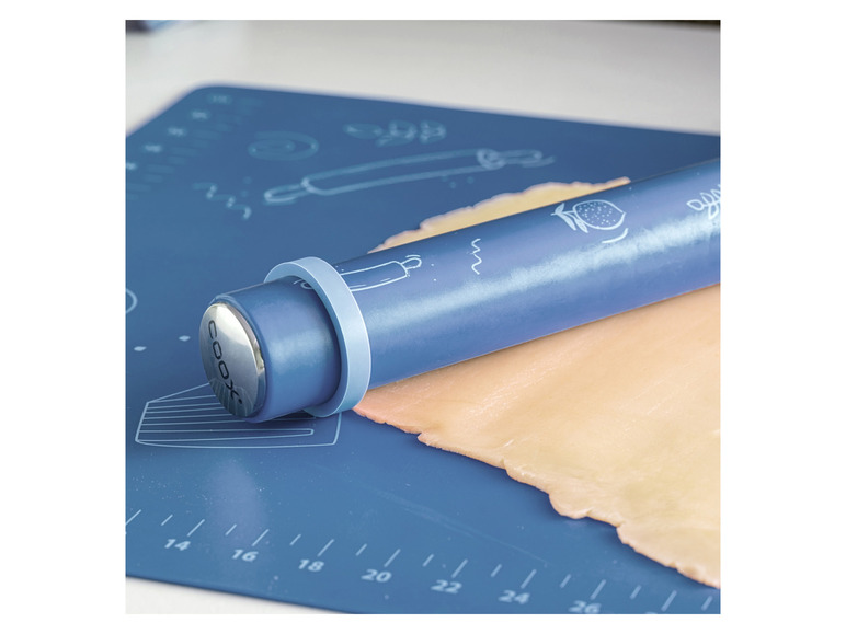 Een blauwe deegroller van Cook op een blauwe bakmat met deeg.